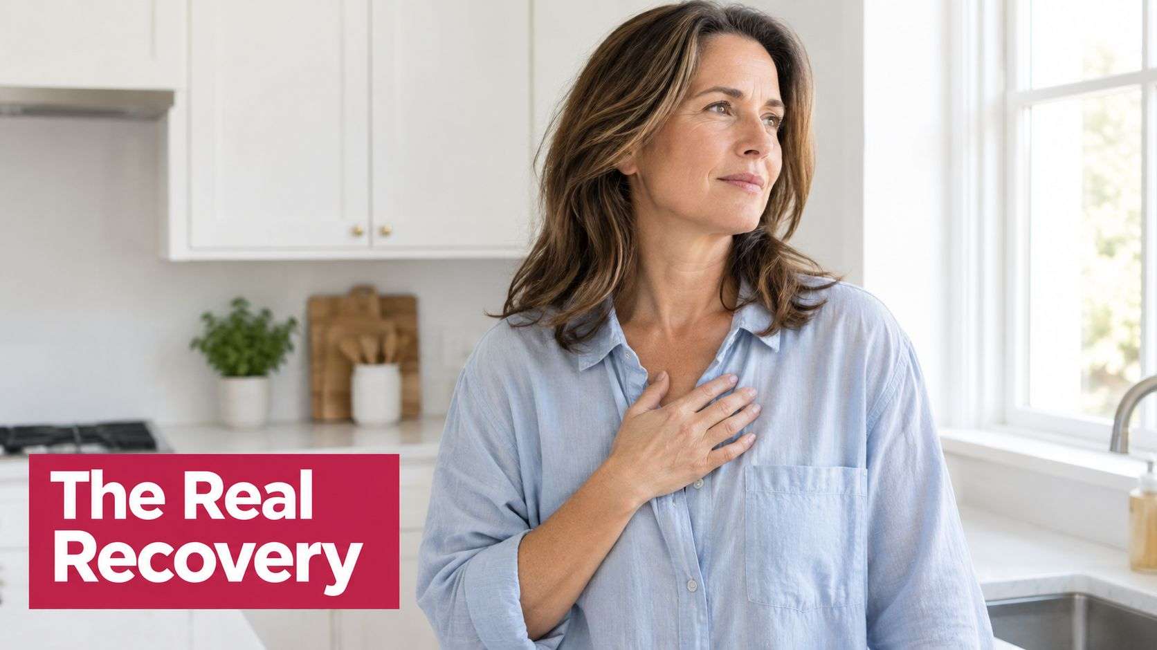 A woman standing in her kitchen with her hand on her chest looking thoughtful and recovered.